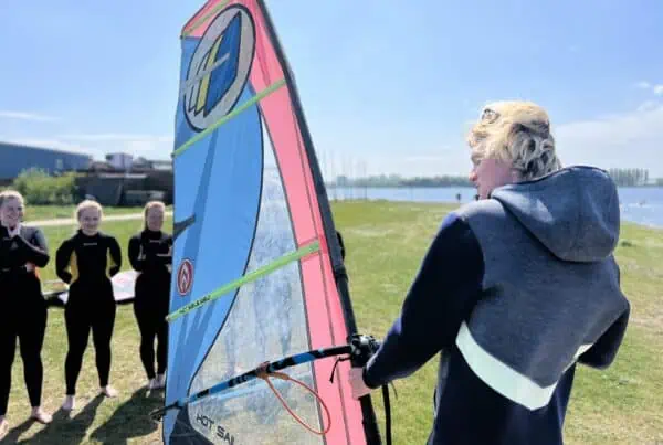 Cursisten met windsurfzeilen op de kant bij GearFreak Surfschool