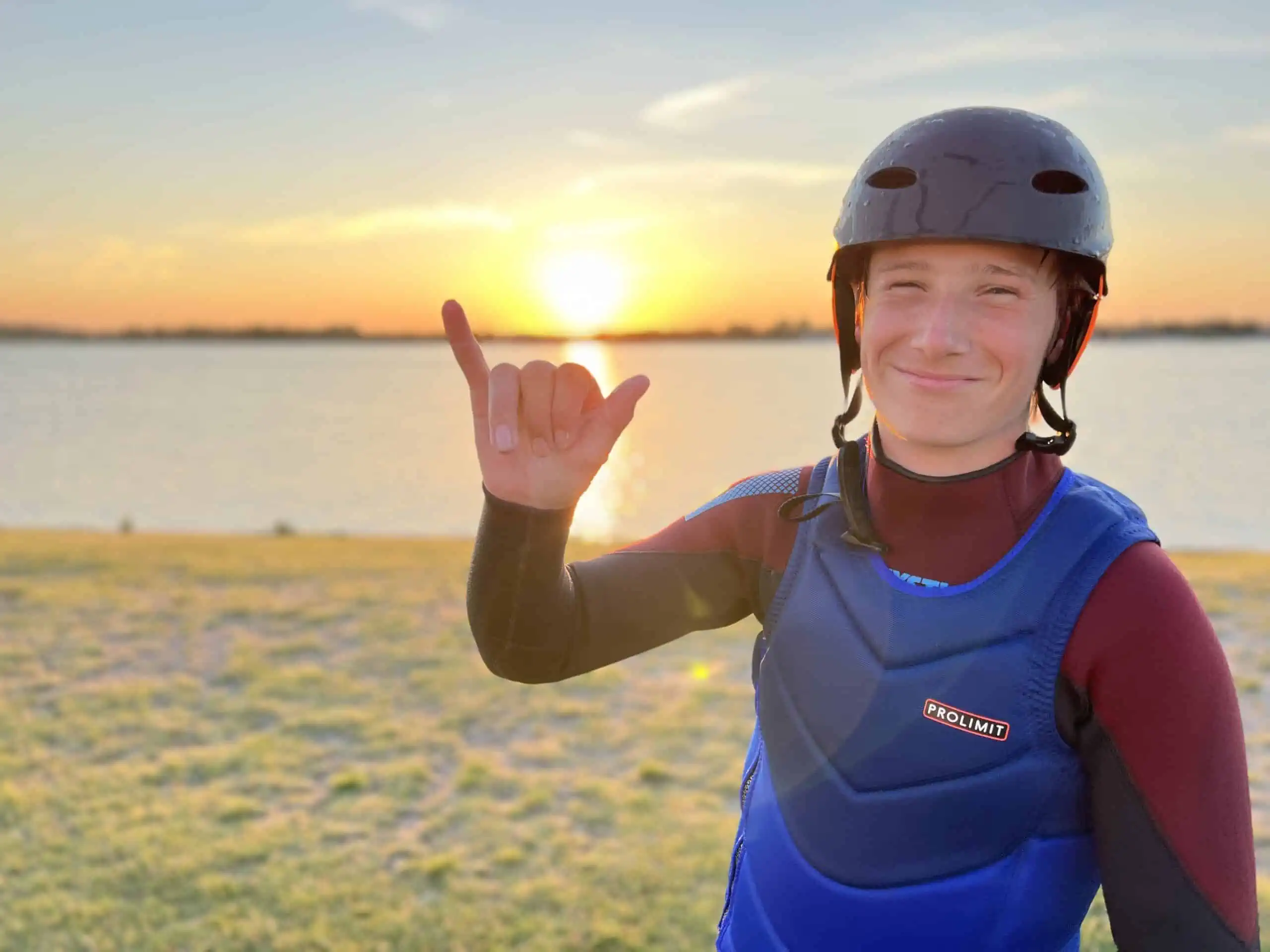Lachende cursist met helm en impactvest bij zonsondergang aan het Valkenburgse Meer