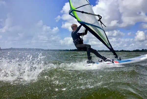 Windsurfer in de trapeze planeert over het Valkenburgse Meer