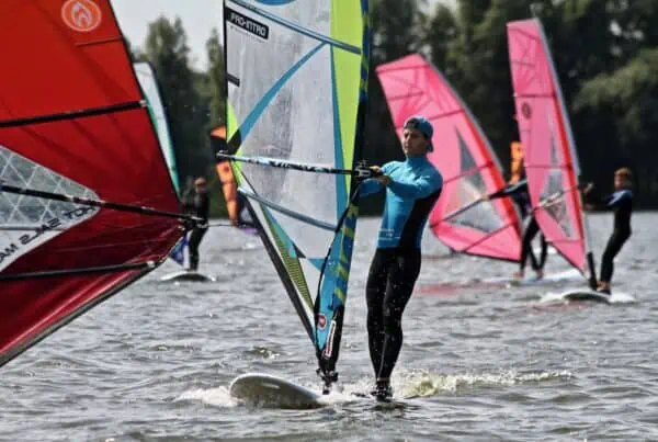 Meerdere windsurfers met kleurrijke zeilen bij GearFreak Surfschool
