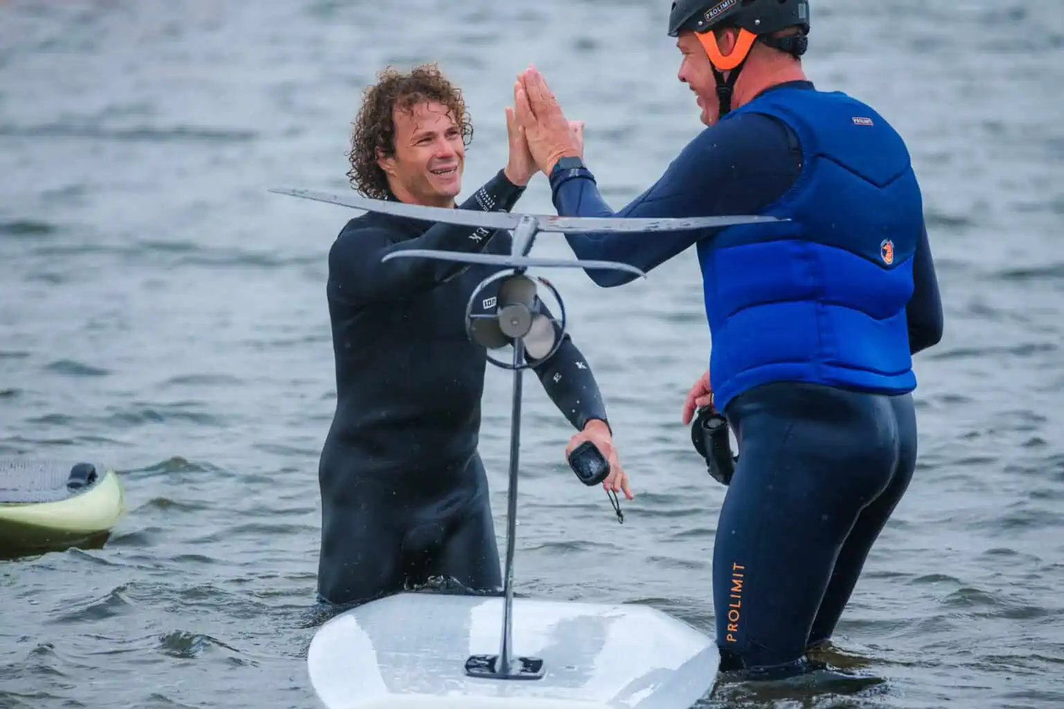 Instructeur en cursist geven elkaar een high five naast een eFoil in het Valkenburgse Meer