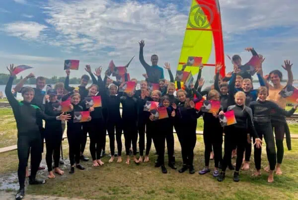 Groep kinderen in wetsuit juicht met hun certificaat na het surfkamp bij GearFreak Surfschool