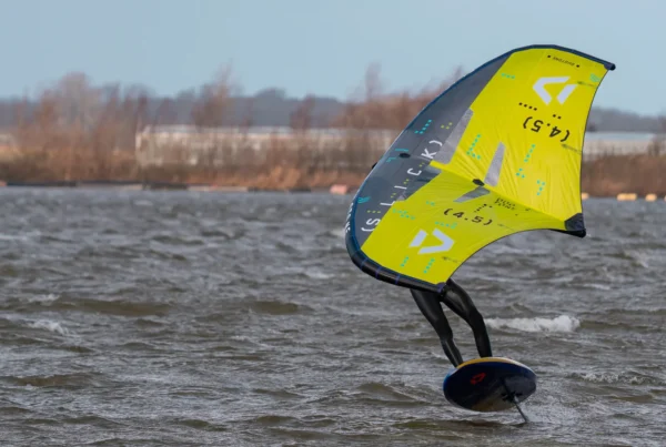 Wingfoiler vliegt met een gele wing over het Valkenburgse Meer bij GearFreak Surfschool
