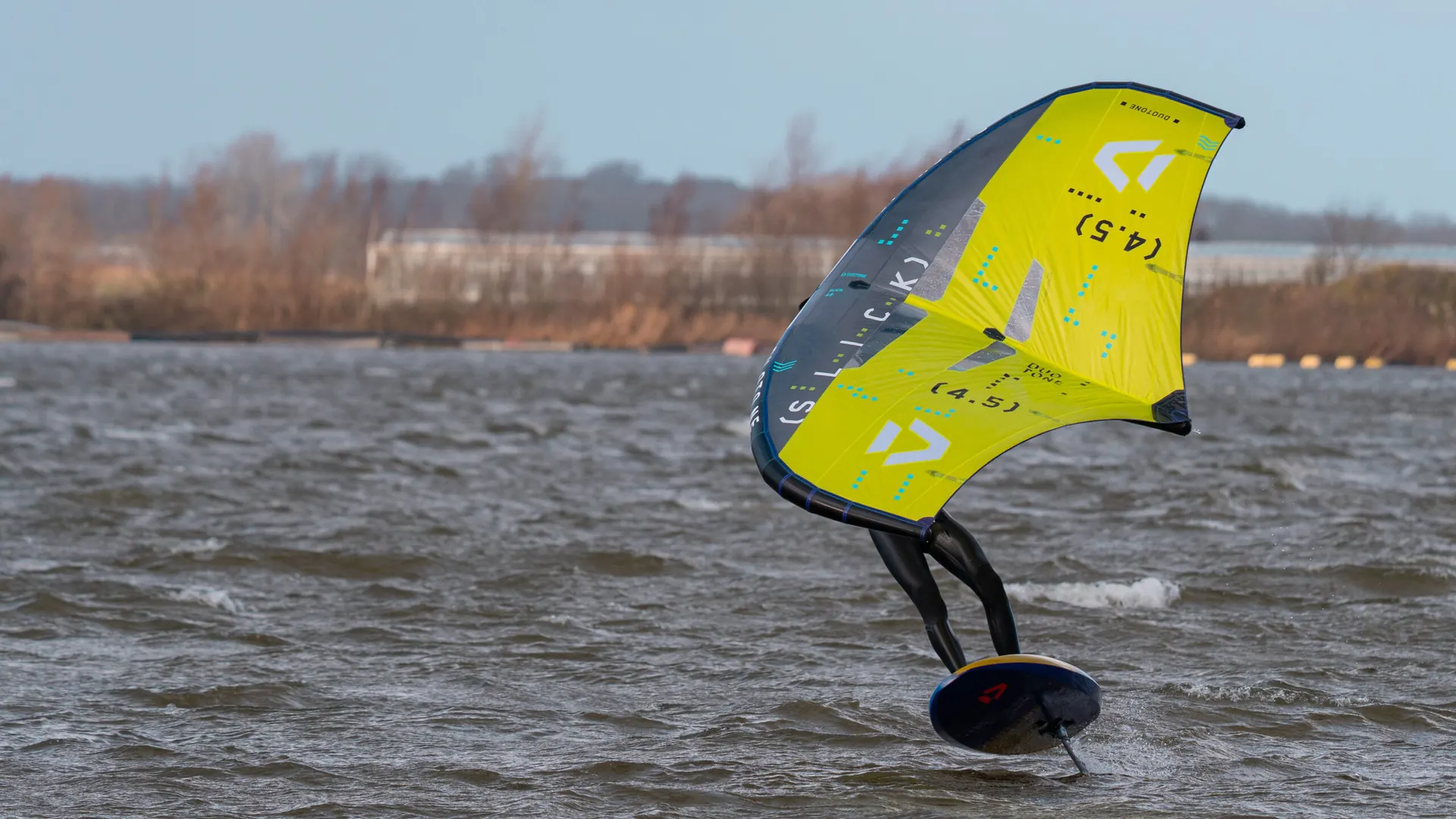 Wingfoiler vliegt met een gele wing over het Valkenburgse Meer bij GearFreak Surfschool